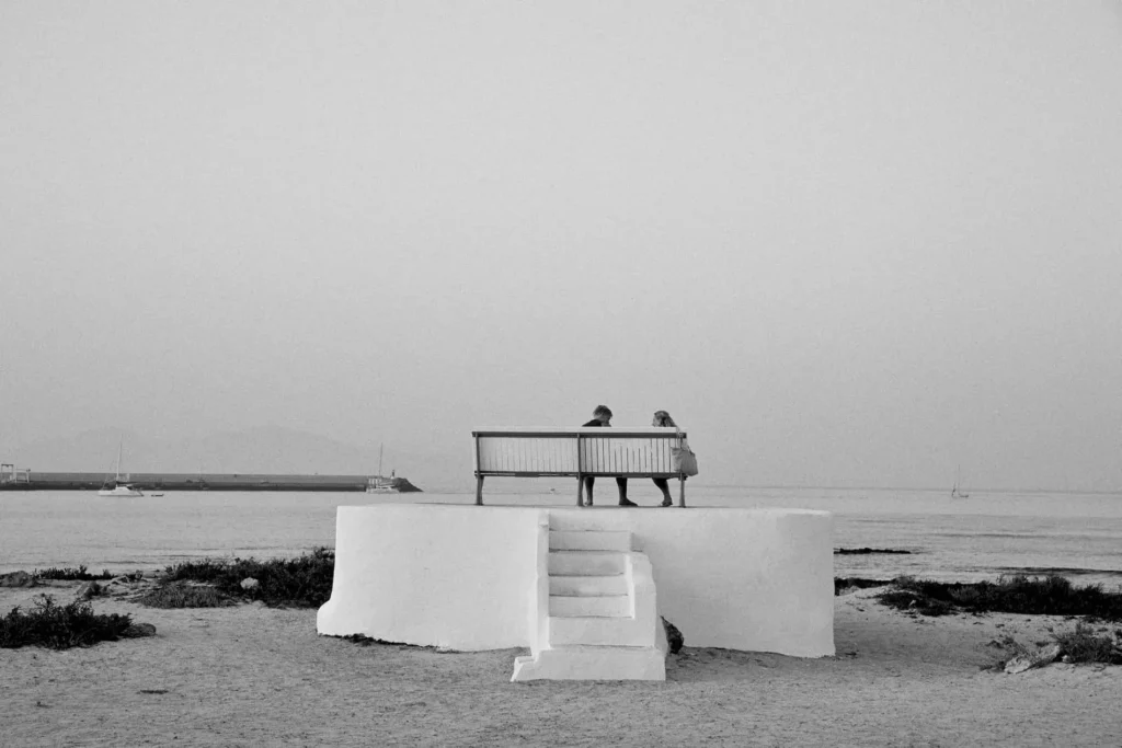 Personas sentadas en un banco frente al mar